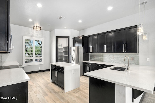 kitchen with light hardwood / wood-style flooring, stainless steel appliances, kitchen peninsula, and sink