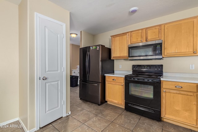 kitchen featuring dark tile floors and black appliances