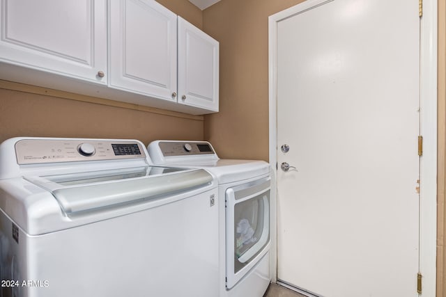 clothes washing area with cabinets and separate washer and dryer