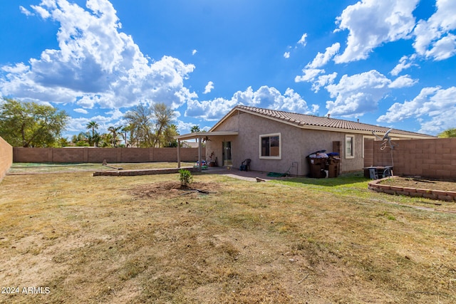 rear view of property featuring a lawn and a patio