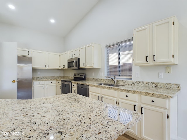 kitchen with sink, stainless steel appliances, white cabinets, and light stone countertops