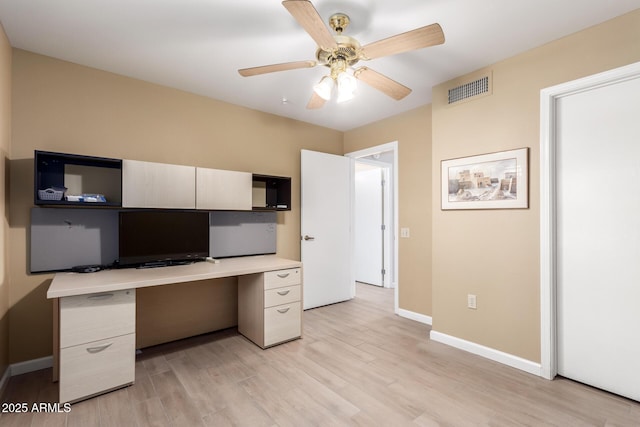 unfurnished office featuring built in desk, light hardwood / wood-style flooring, and ceiling fan