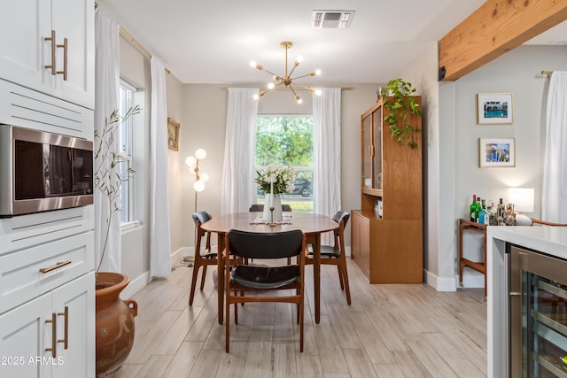 1702 W Glenrosa Ave, Phoenix, AZ 85015 - dining space featuring beverage cooler, a chandelier, light wood-style floors, and baseboards