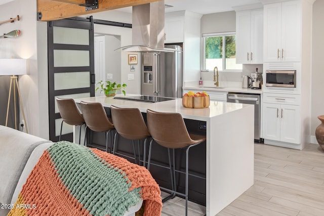 1702 W Glenrosa Ave, Phoenix, AZ 85015 - kitchen featuring stainless steel appliances, island exhaust hood, a sink, a breakfast bar, and white cabinetry