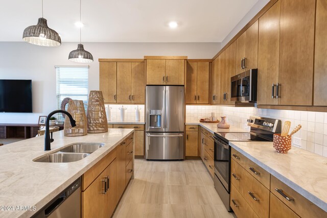 kitchen with appliances with stainless steel finishes, pendant lighting, tasteful backsplash, and sink