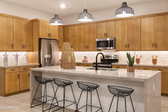 kitchen with pendant lighting, stainless steel appliances, sink, and a center island with sink