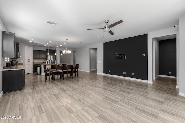 dining space with ceiling fan with notable chandelier