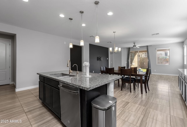 kitchen featuring light stone countertops, sink, pendant lighting, a kitchen island with sink, and ceiling fan with notable chandelier