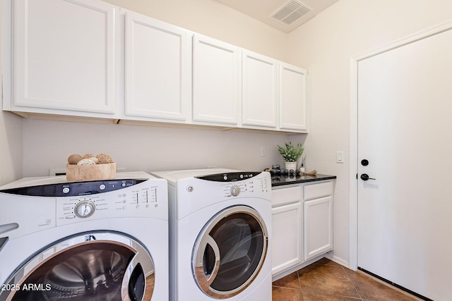 laundry area with visible vents, dark tile patterned flooring, washing machine and clothes dryer, and cabinet space