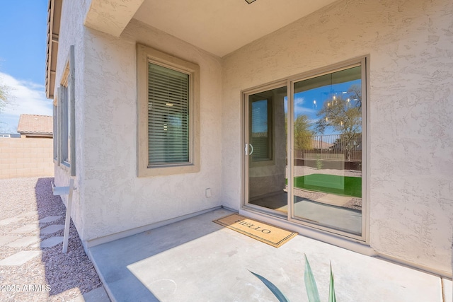 doorway to property featuring a patio area, fence, and stucco siding