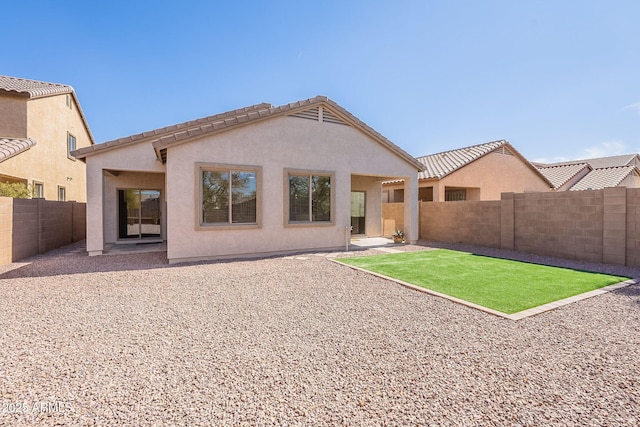 rear view of house with a tile roof, a patio area, a fenced backyard, and stucco siding