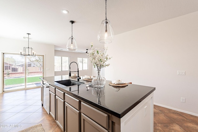 kitchen featuring baseboards, dishwasher, decorative light fixtures, a kitchen island with sink, and a sink