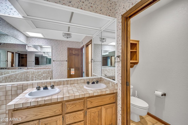 7037 N 11th Dr, Phoenix, AZ 85021 - full bath with wallpapered walls, double vanity, toilet, baseboards, and tile patterned floors
