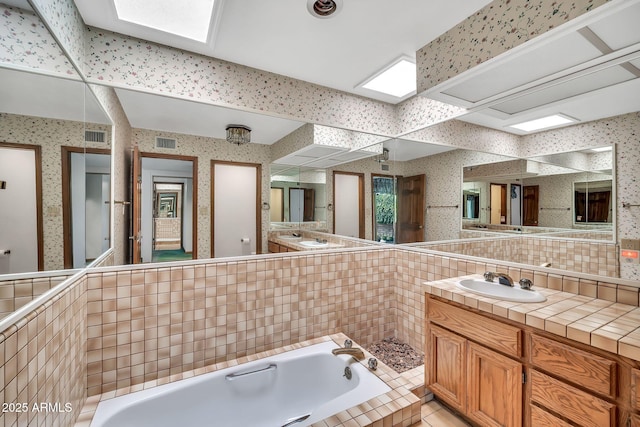 7037 N 11th Dr, Phoenix, AZ 85021 - full bath with wallpapered walls, a bath, vanity, tasteful backsplash, and a skylight