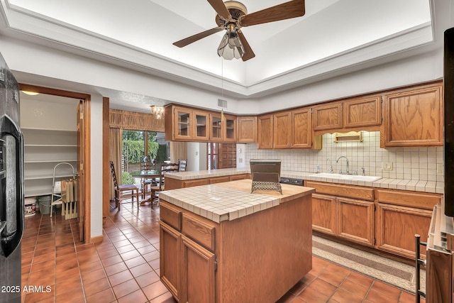 7037 N 11th Dr, Phoenix, AZ 85021 - kitchen featuring a sink, tile counters, tile patterned flooring, brown cabinets, and a ceiling fan