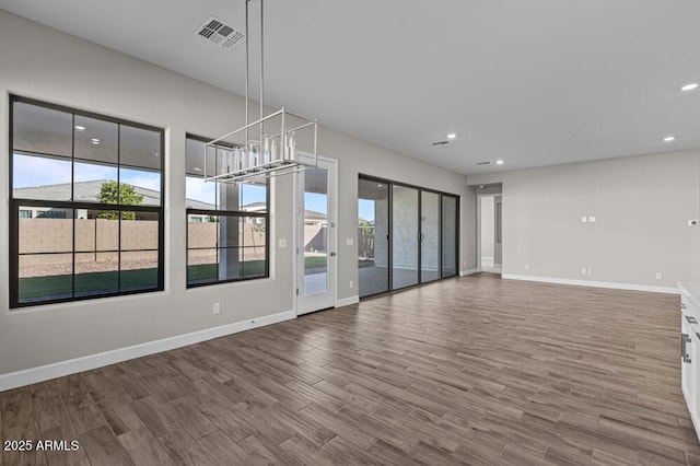 empty room with baseboards, visible vents, wood finished floors, and recessed lighting