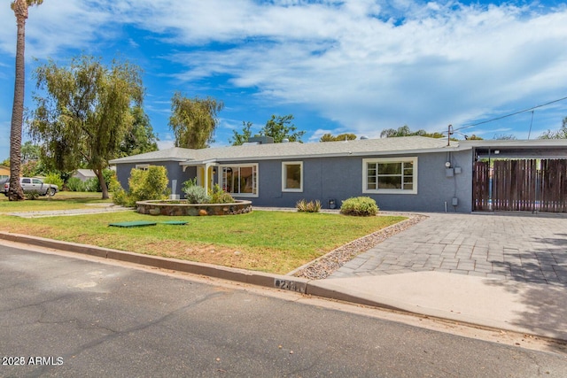 ranch-style house featuring a front lawn, decorative driveway, and stucco siding