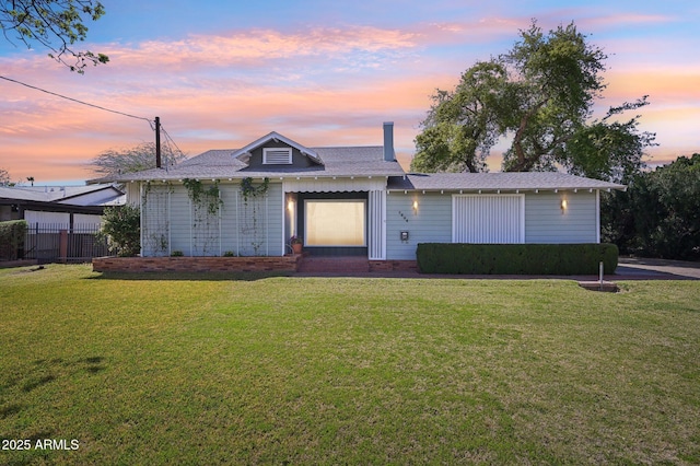 view of front of home featuring a lawn and roof with shingles