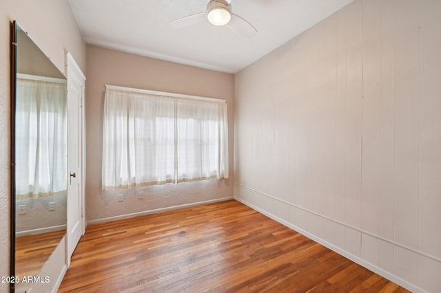 spare room with baseboards, ceiling fan, and wood finished floors