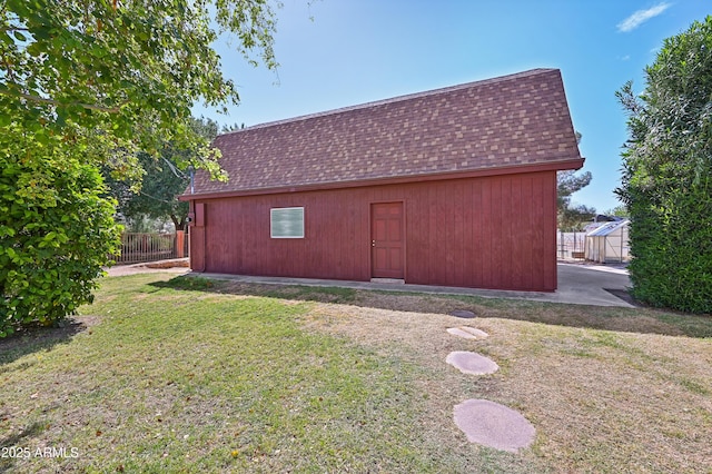 view of outdoor structure with fence and an outbuilding