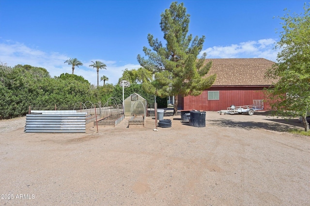 exterior space with an outbuilding, a greenhouse, and a vegetable garden