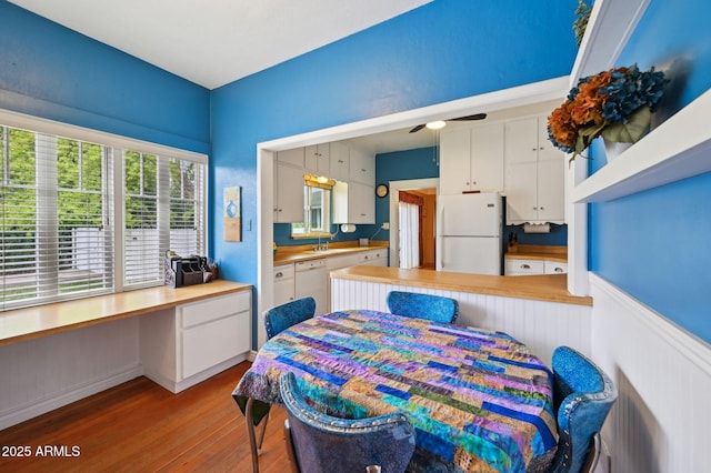 dining space with built in study area, ceiling fan, and wood finished floors