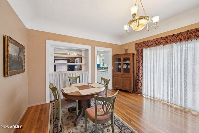 dining area featuring an inviting chandelier, baseboards, built in features, and wood finished floors
