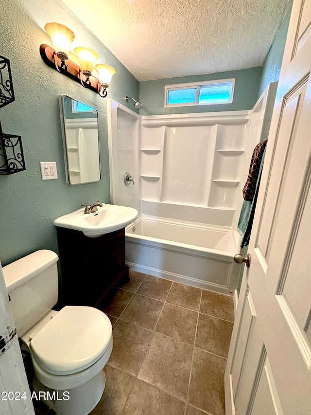 full bathroom with washtub / shower combination, tile patterned flooring, a textured ceiling, toilet, and vanity