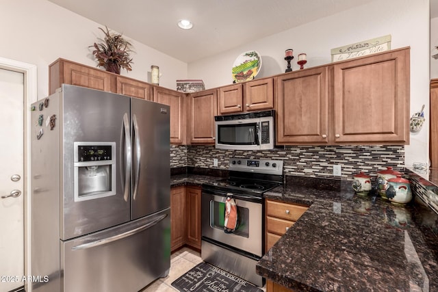 kitchen with light tile patterned floors, decorative backsplash, dark stone counters, and appliances with stainless steel finishes