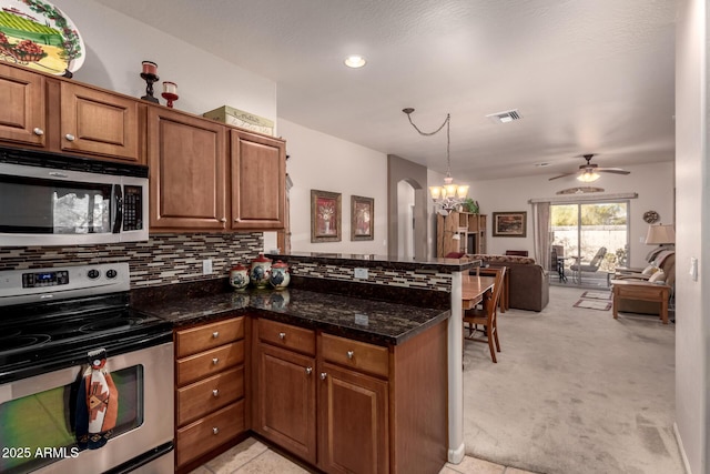 kitchen with light carpet, decorative backsplash, dark stone counters, and appliances with stainless steel finishes