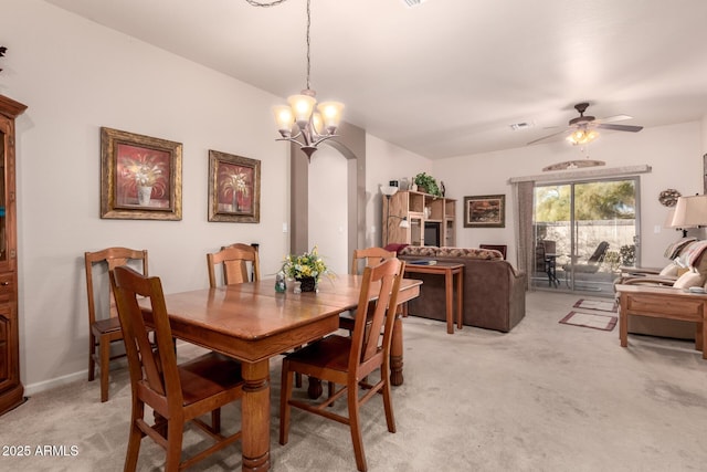 dining area with ceiling fan with notable chandelier and light colored carpet