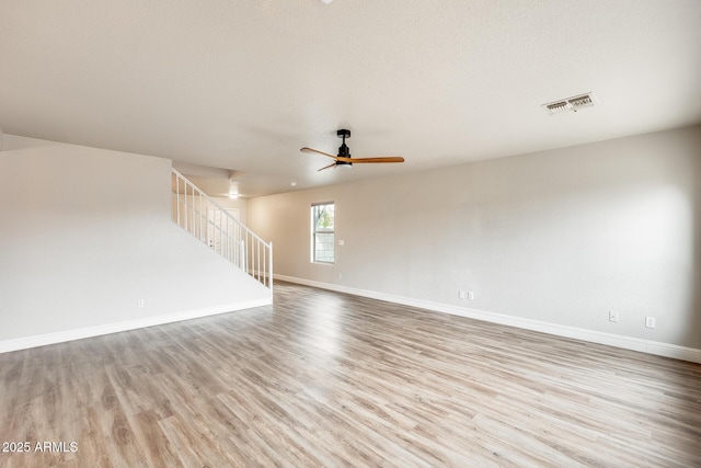 empty room with visible vents, baseboards, wood finished floors, and stairs