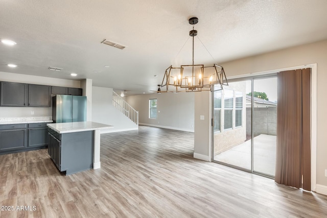 kitchen featuring visible vents, light countertops, gray cabinets, freestanding refrigerator, and light wood-style floors