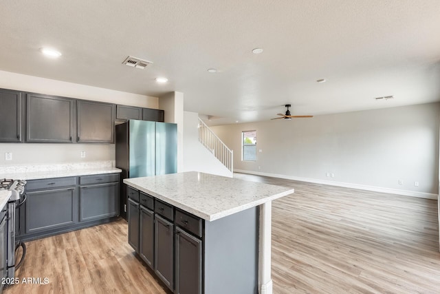 kitchen with light wood-style flooring, baseboards, visible vents, and a center island