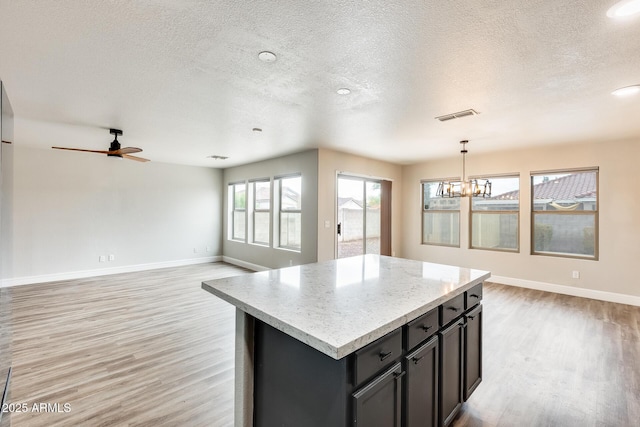 kitchen featuring light wood finished floors, visible vents, a center island, and open floor plan