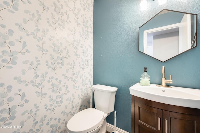 bathroom featuring toilet, vanity, and a textured wall