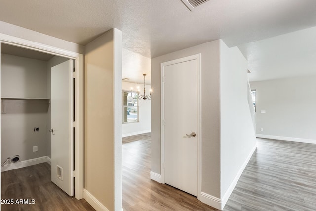 hallway with wood finished floors, visible vents, and baseboards