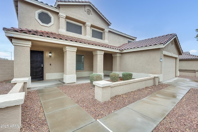 view of front of home with stucco siding, a garage, covered porch, and a tiled roof