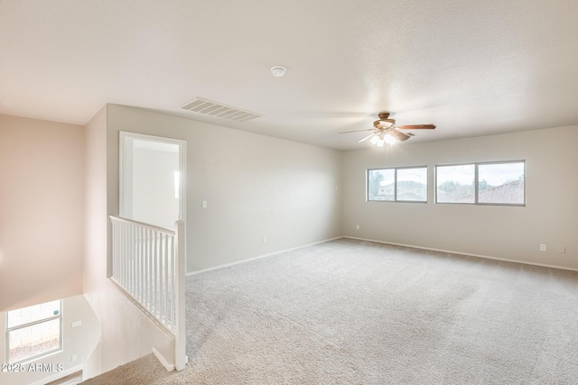 carpeted empty room featuring visible vents, baseboards, and ceiling fan