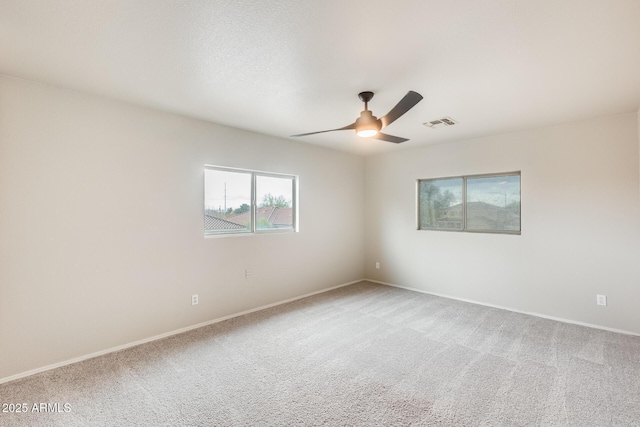 empty room featuring ceiling fan, baseboards, visible vents, and light carpet