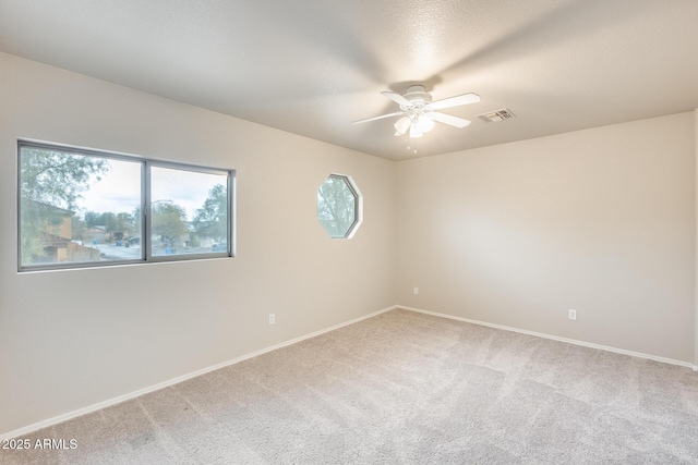 empty room with visible vents, baseboards, a ceiling fan, and carpet floors