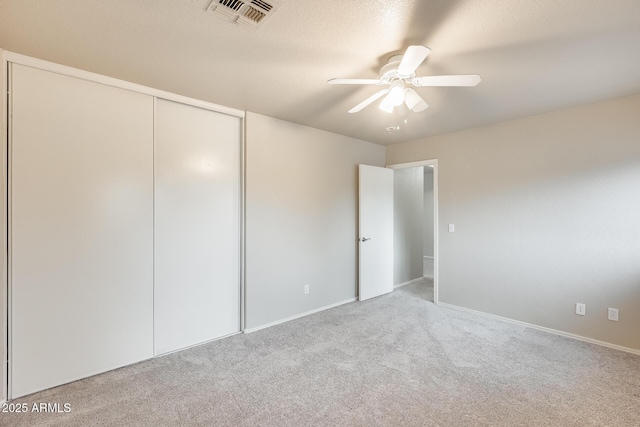 unfurnished bedroom with visible vents, carpet floors, ceiling fan, a closet, and a textured ceiling