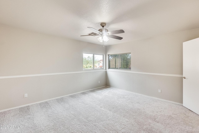 carpeted empty room with visible vents, baseboards, and a ceiling fan