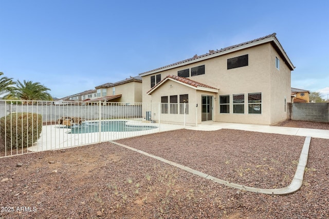 back of house featuring a fenced in pool, a tile roof, stucco siding, a fenced backyard, and a patio area