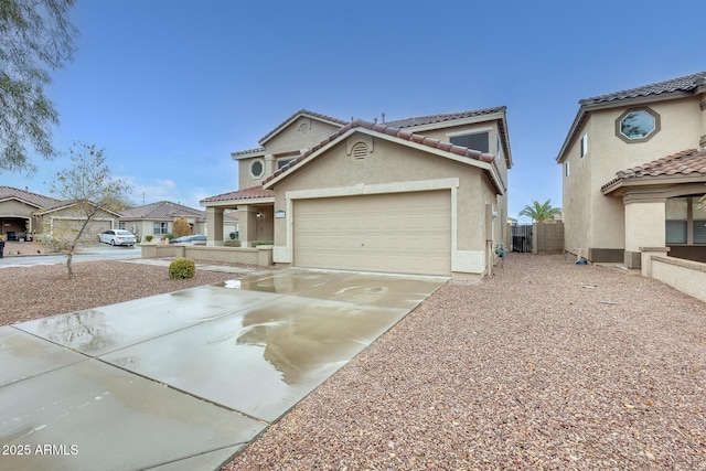 mediterranean / spanish home with fence, a tile roof, concrete driveway, stucco siding, and a garage