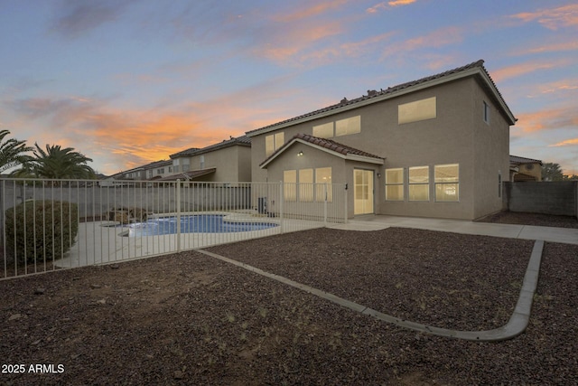 back of house at dusk with a patio area, stucco siding, and a fenced backyard