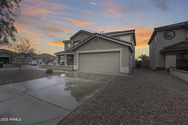 traditional home with concrete driveway, a tiled roof, an attached garage, and stucco siding