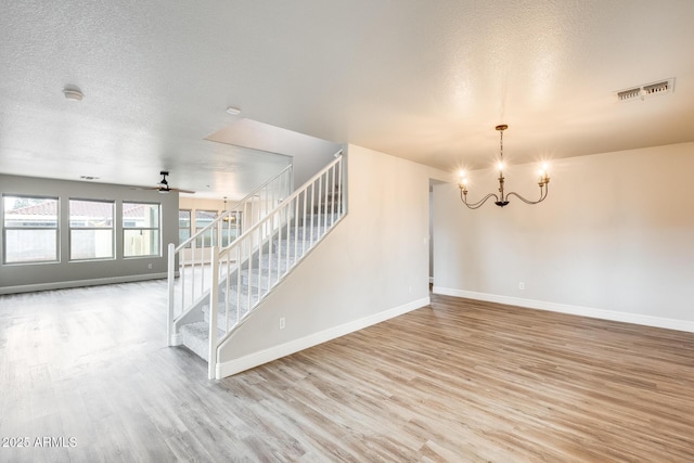 spare room with stairway, visible vents, light wood finished floors, and a textured ceiling