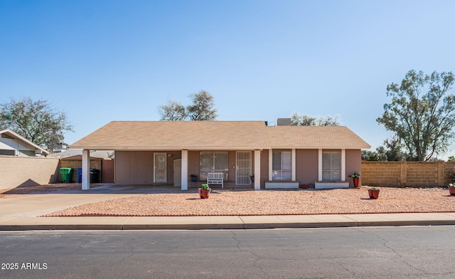 single story home featuring an attached carport, concrete driveway, and fence