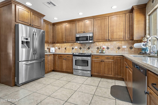 kitchen with brown cabinetry, visible vents, appliances with stainless steel finishes, and a sink